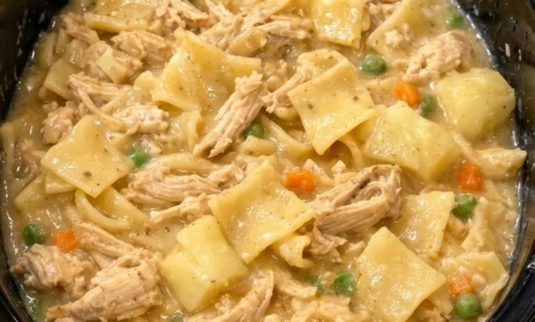 Creamy crockpot chicken pot pie soup with shredded chicken, potatoes, vegetables, and egg noodles in a slow cooker.